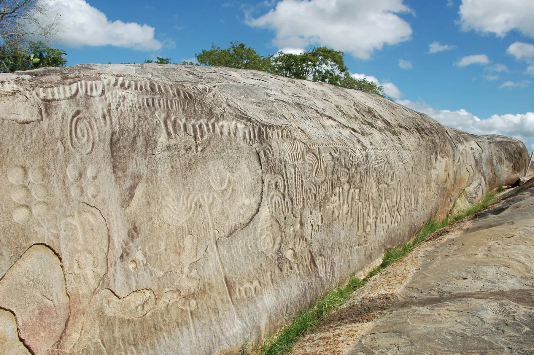 Pedra do Ingá com inscrições gravadas na rocha sob céu azul