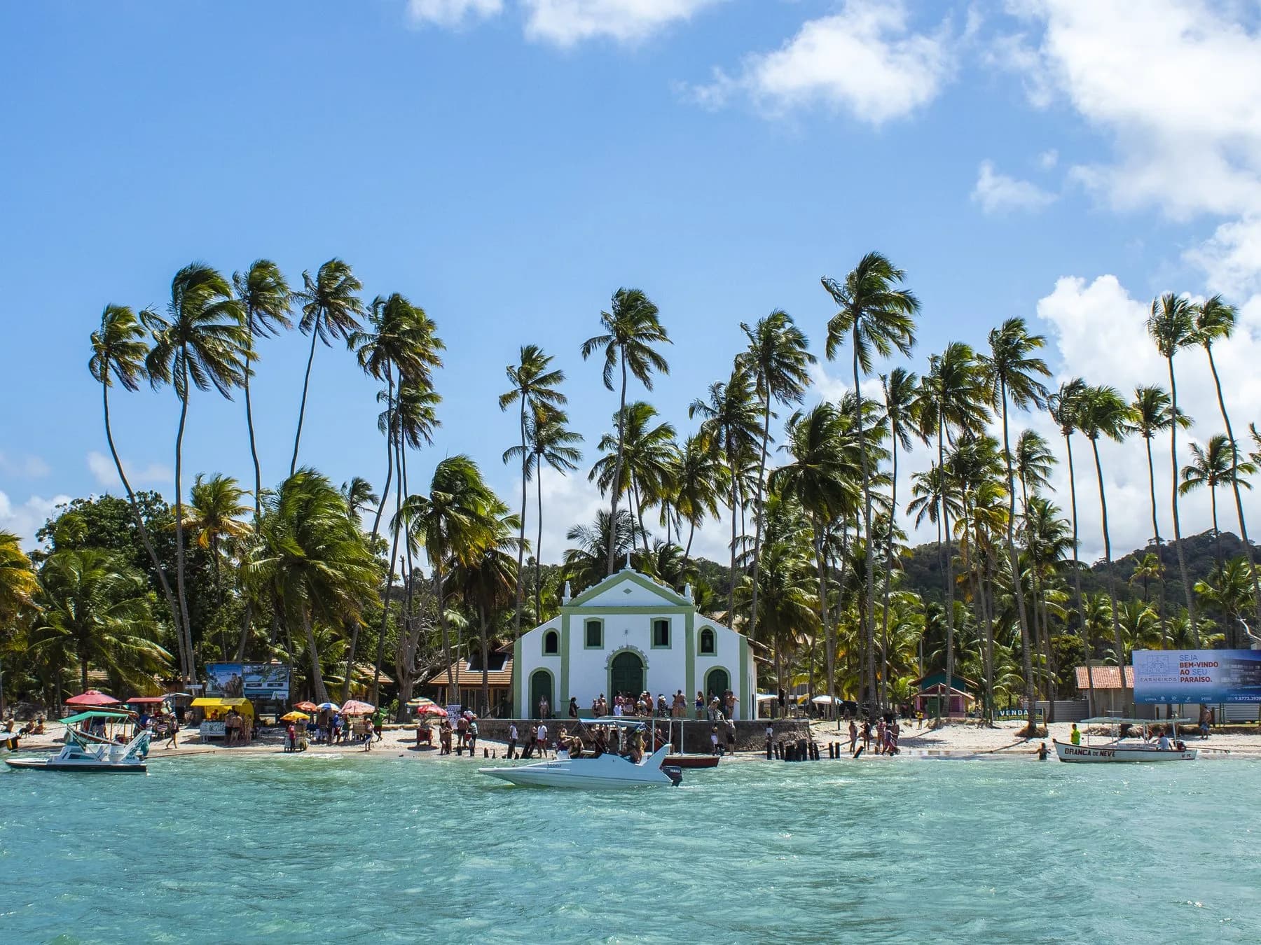 Passeio à Praia dos Carneiros com a Igreja de São Benedito, coqueiros, barcos e visitantes na praia