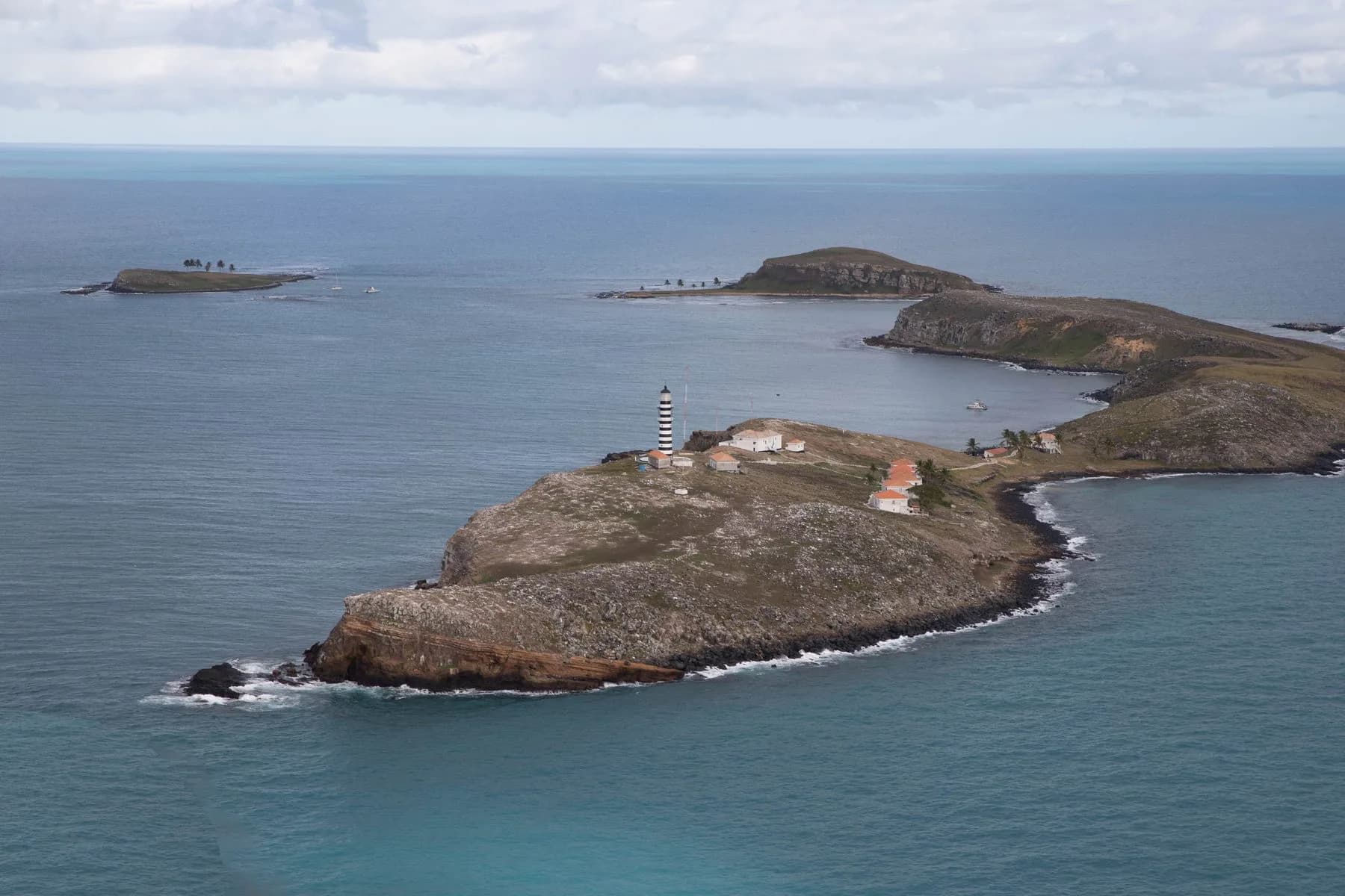 Arquipélago de Abrolhos visto do alto, com ilha rochosa e farol listrado
