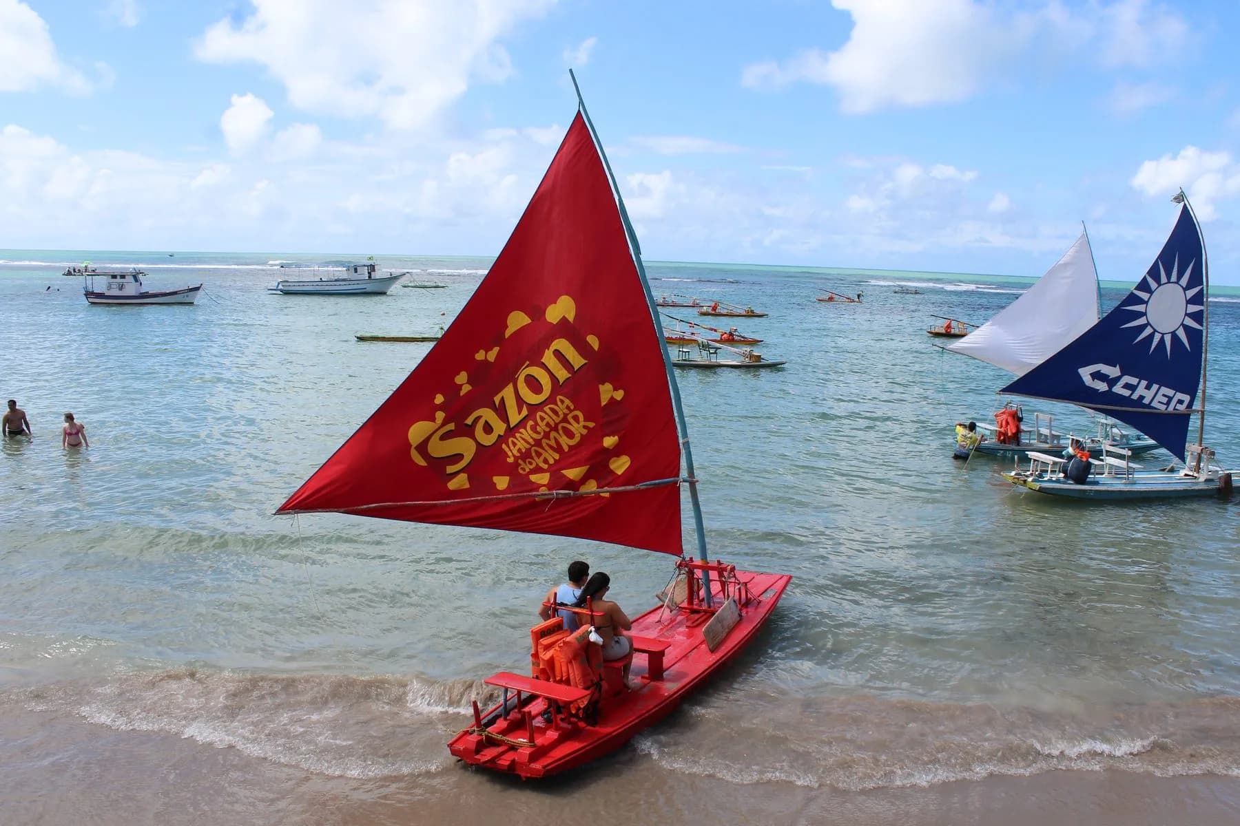 Jangada vermelha nas piscinas naturais de Porto de Galinhas, com barcos ao fundo