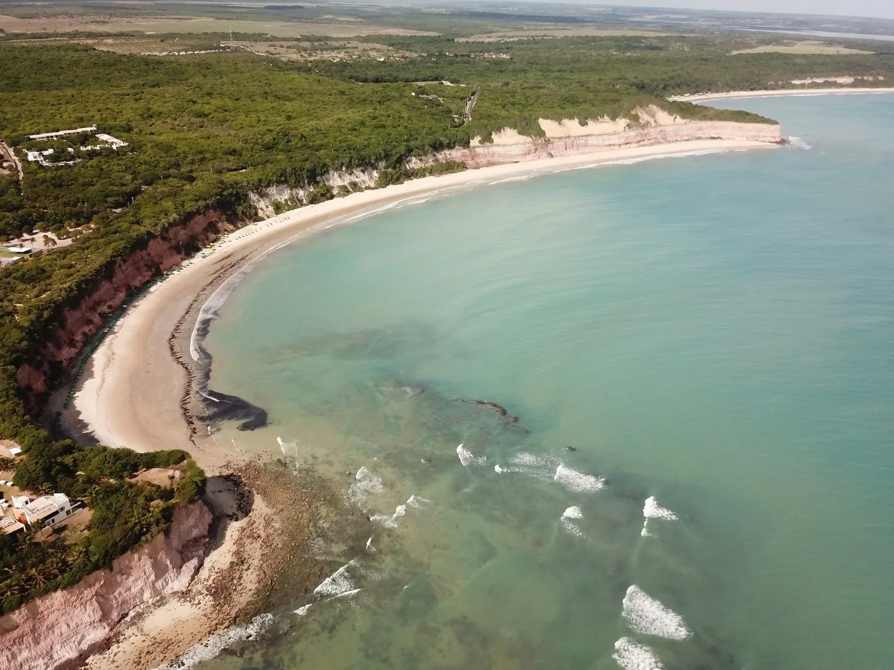Baía dos Golfinhos, em Pipa, vista do barco entre falésias e mar azul