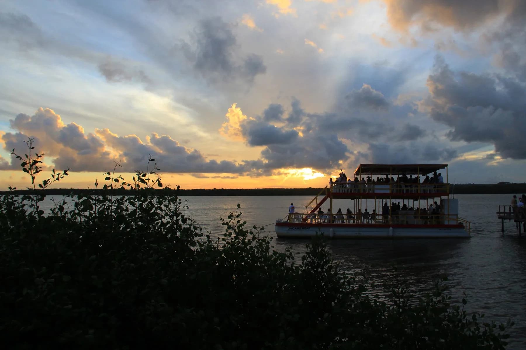 Catamarã do passeio ao pôr do sol no Rio Jacaré, cercado por passageiros e águas tranquilas